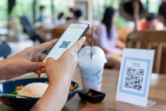 Iemand scant in een restaurant een QR code met zijn smartphone.
