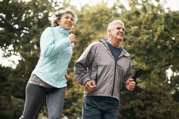 Man en vrouw joggen samen in een groene omgeving.