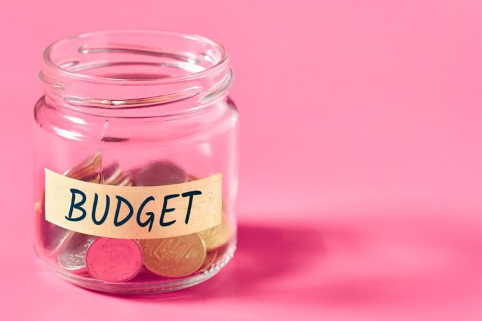 Glazen potje gevuld met muntgeld met het woord 'budget' erop.