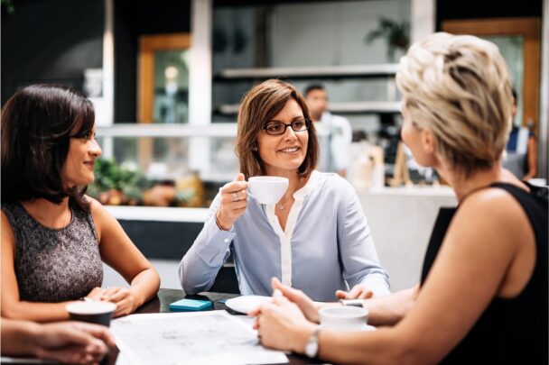 Drie vrouwen drinken samen koffie.