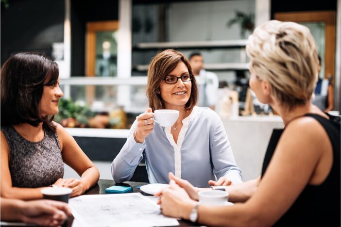 Drie vrouwen drinken samen koffie.