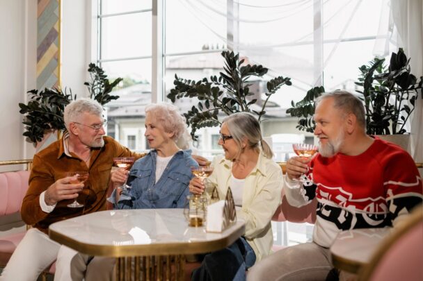 Twee mannen en twee vrouwen zitten te kletsen en wat te drinken aan een tafel.