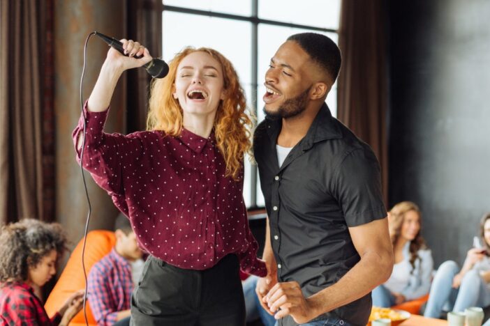 Jonge man en vrouw zingen samen in een microfoon.
