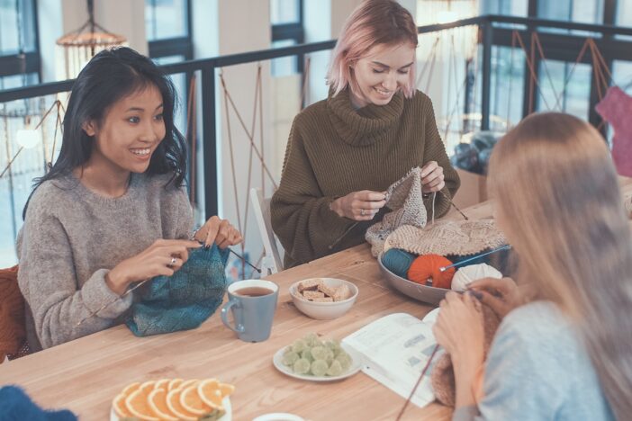 Vrouwen zitten samen te breien aan tafel.