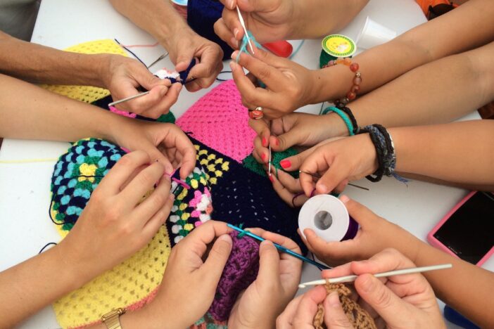 Aantal paar handen is samen aan het haken.