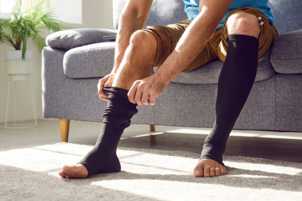 Man trekt steunkous aan