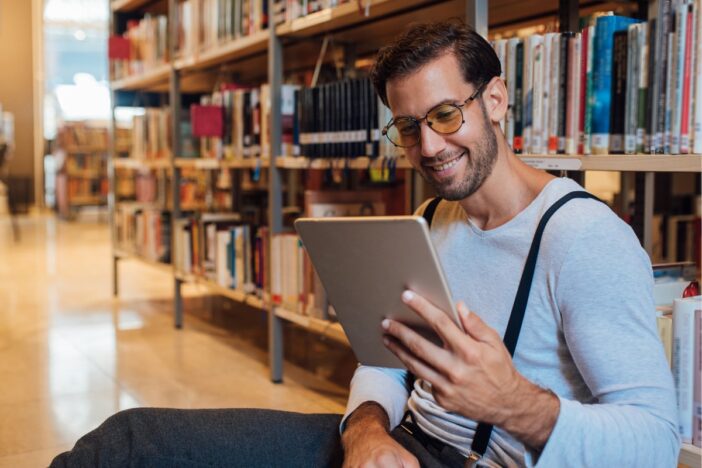 Man lees een boek in e bibliotheek.