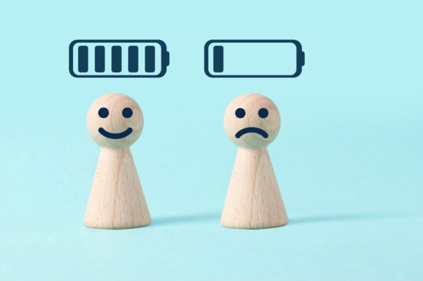 Illustratie van een houten poppetje met lege batterj en een houten poppetje met volle batterij.