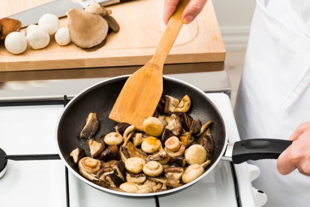 Pan met champignons waar iemand in roert