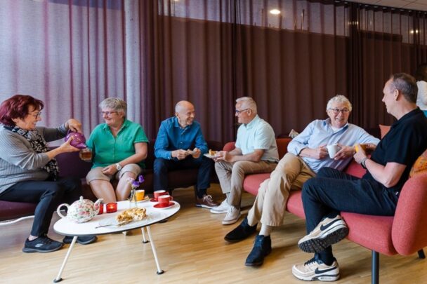 Groep mensen met koffie in luie stoelen praten me elkaar.