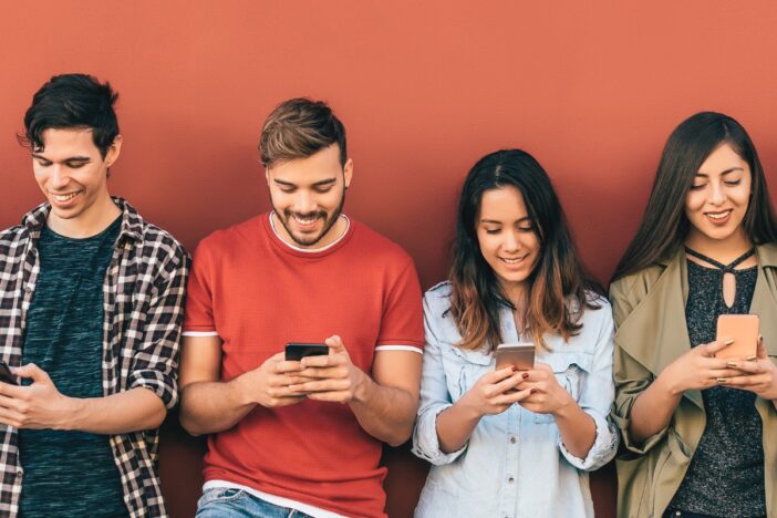 4 jongeren op rij met smarthpone in de hand