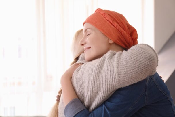 Vrouw door chemo zonder haar met hoofddoek knuffelt