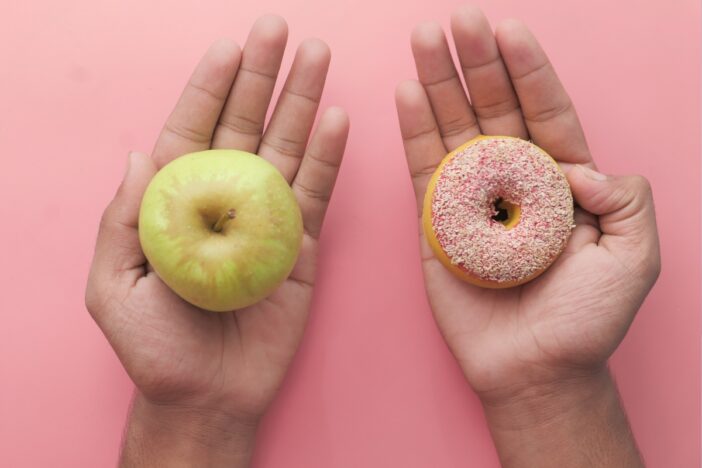 Hand met appel en hand met donut erop.