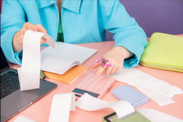 Vrouw is bezig met allerlei papierwerk aan een bureau.