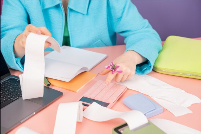 Vrouw is bezig met allerlei papierwerk aan een bureau.