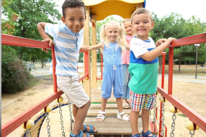 Drie jonge kinderen spelen samen op een klimtoestel.