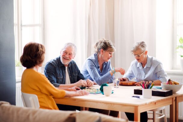 Vier oudere mensen hebben een gesprek aan tafel.