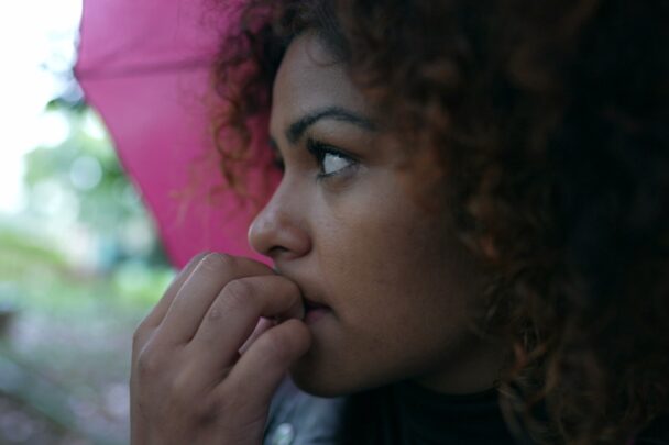 Vrouw kijkt bezorgd en bijt aan haar nagels.