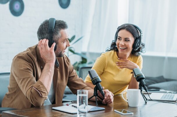 Man en vrouw maken samen een geluidsopname aan tafel.