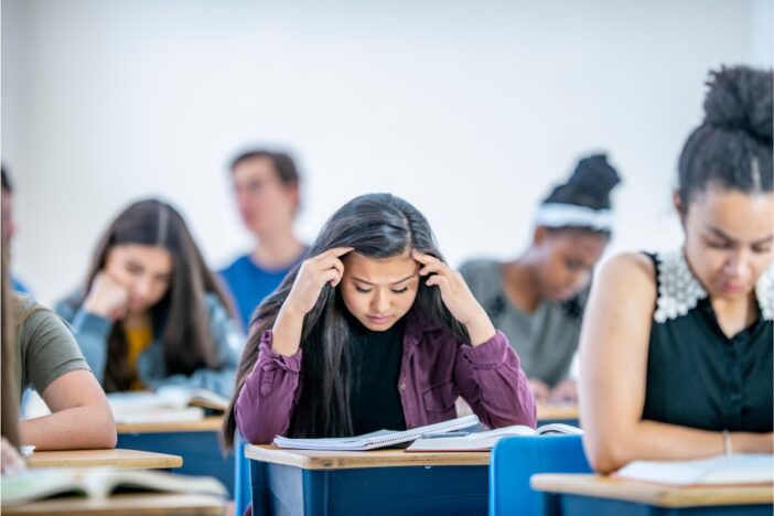Studenten maken een toets in een schoolsetting. Een meisje oogt duidelijk gestresst.