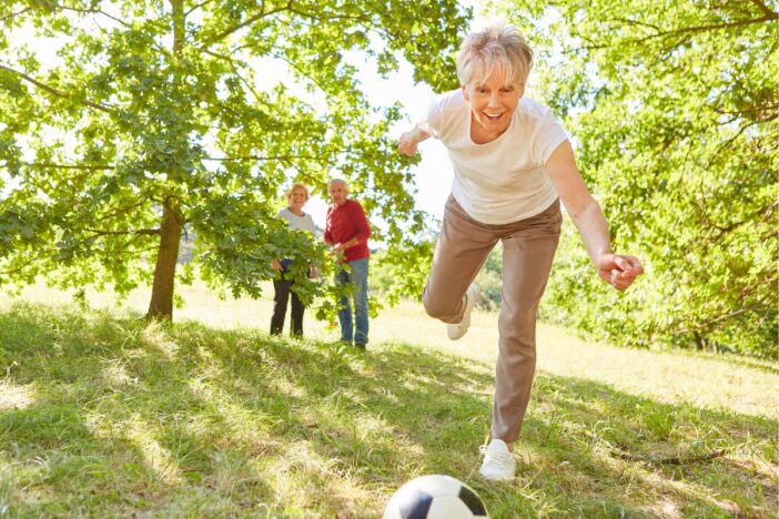 Oudere vrouw speelt voetbal op het gras