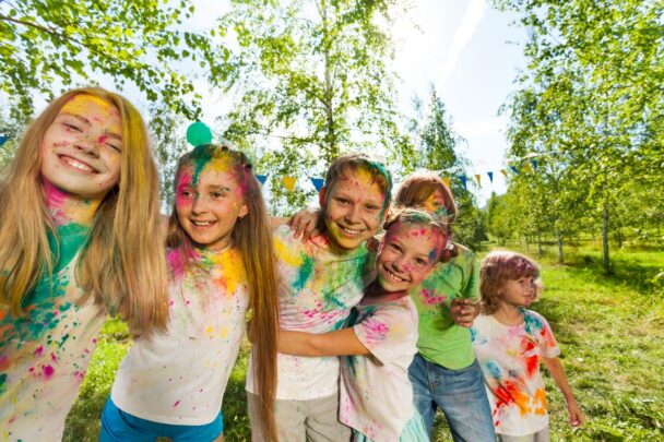 Kinderen spelen buiten met verf en hebben het leuk samen. Ze lachen.