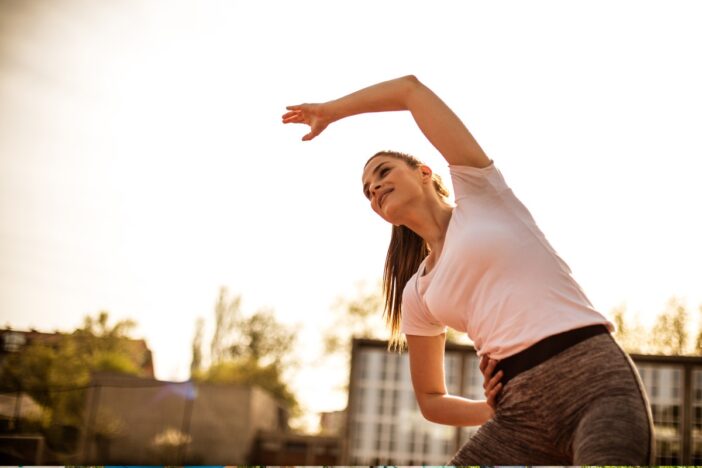Vrouw doet een stretchoefening in buitenlucht.
