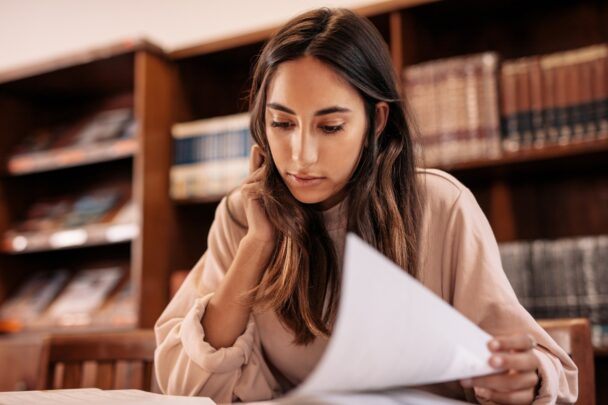 Jonge vrouw is aan het lezen of studeren in een bibliotheek.