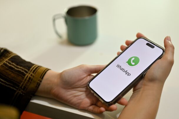Iemand houdt een smartphone vast waarop de app Whatsapp te zien is.