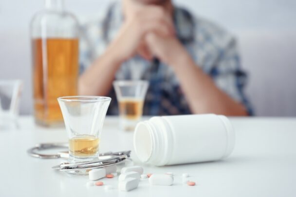 Man zit aan een tafel met daarop alcohol en pillen uitgestald