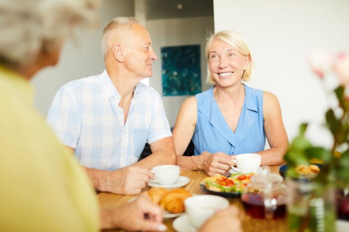 Ouderen eten en drinken samen wat aan tafel.