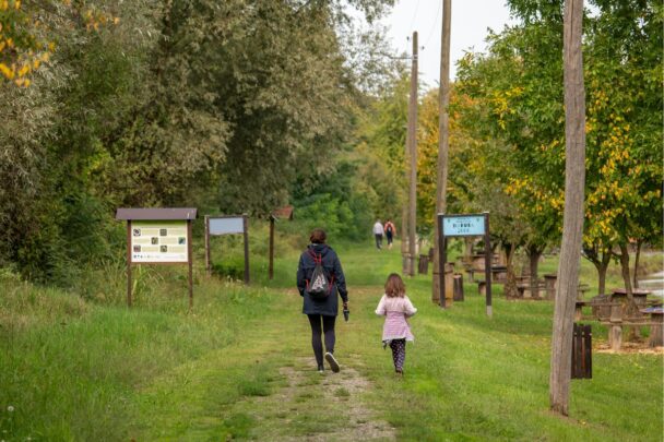 Moeder en kind wandelen samen in bosrijke omgeving.
