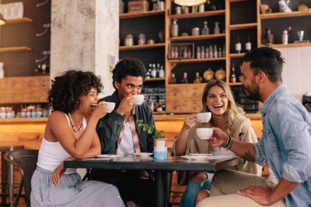 Vier mensen drinken samen koffie en lachen.